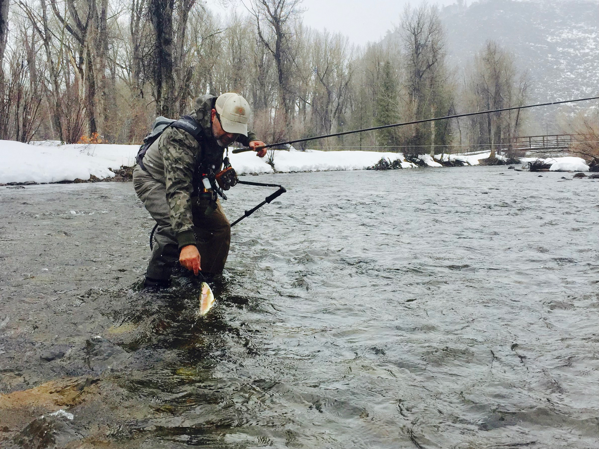 Angler fishing during the winter holding his rod and fish